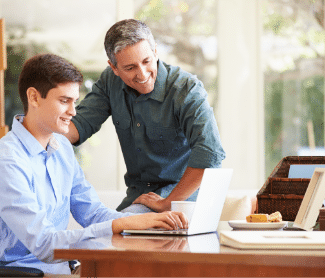 Boy and his dad looking at a laptop